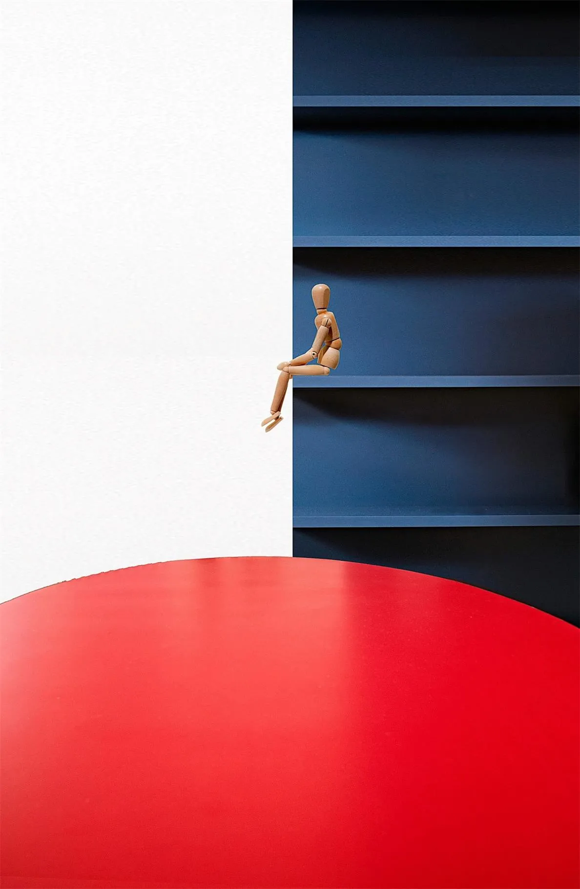 A minimalist interior design featuring a white wall and blue shelves with a red floor.