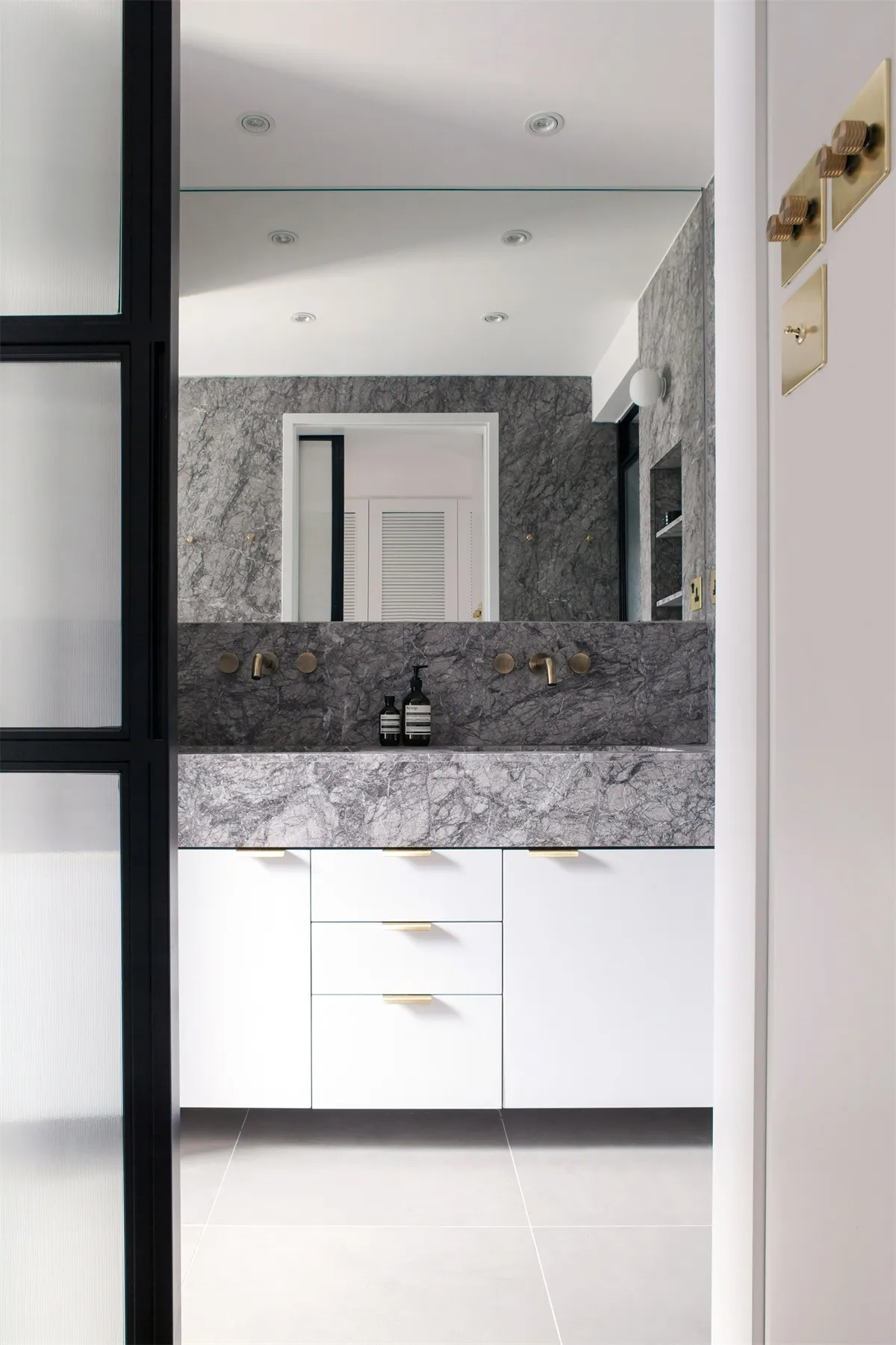 Modern bathroom featuring a marble countertop and vanity with white cabinets.