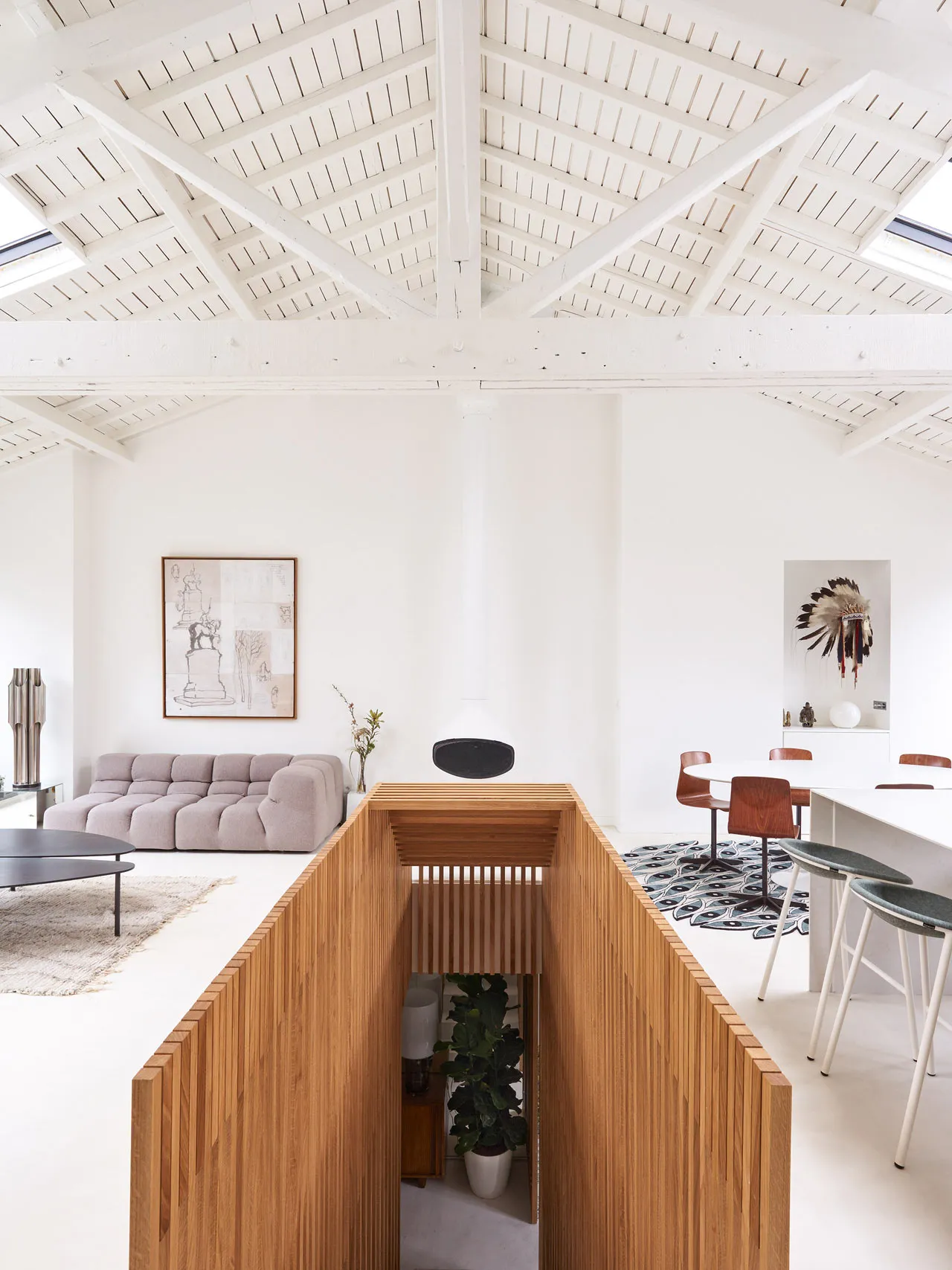 A modern living and dining room with wooden walls and white walls, featuring a wooden partition and a round coffee table in t