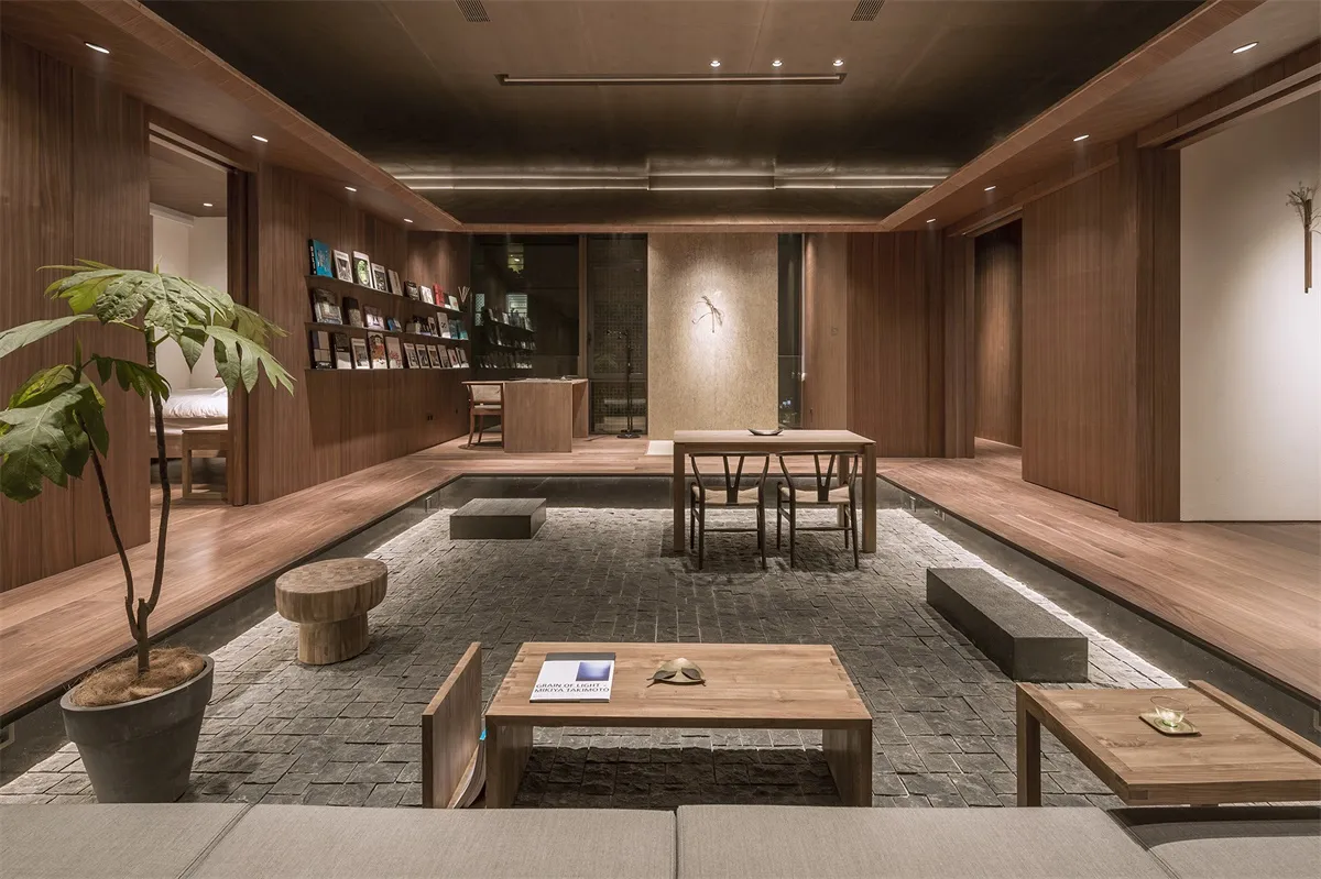 A modern minimalist living space with wooden furniture and a potted plant.