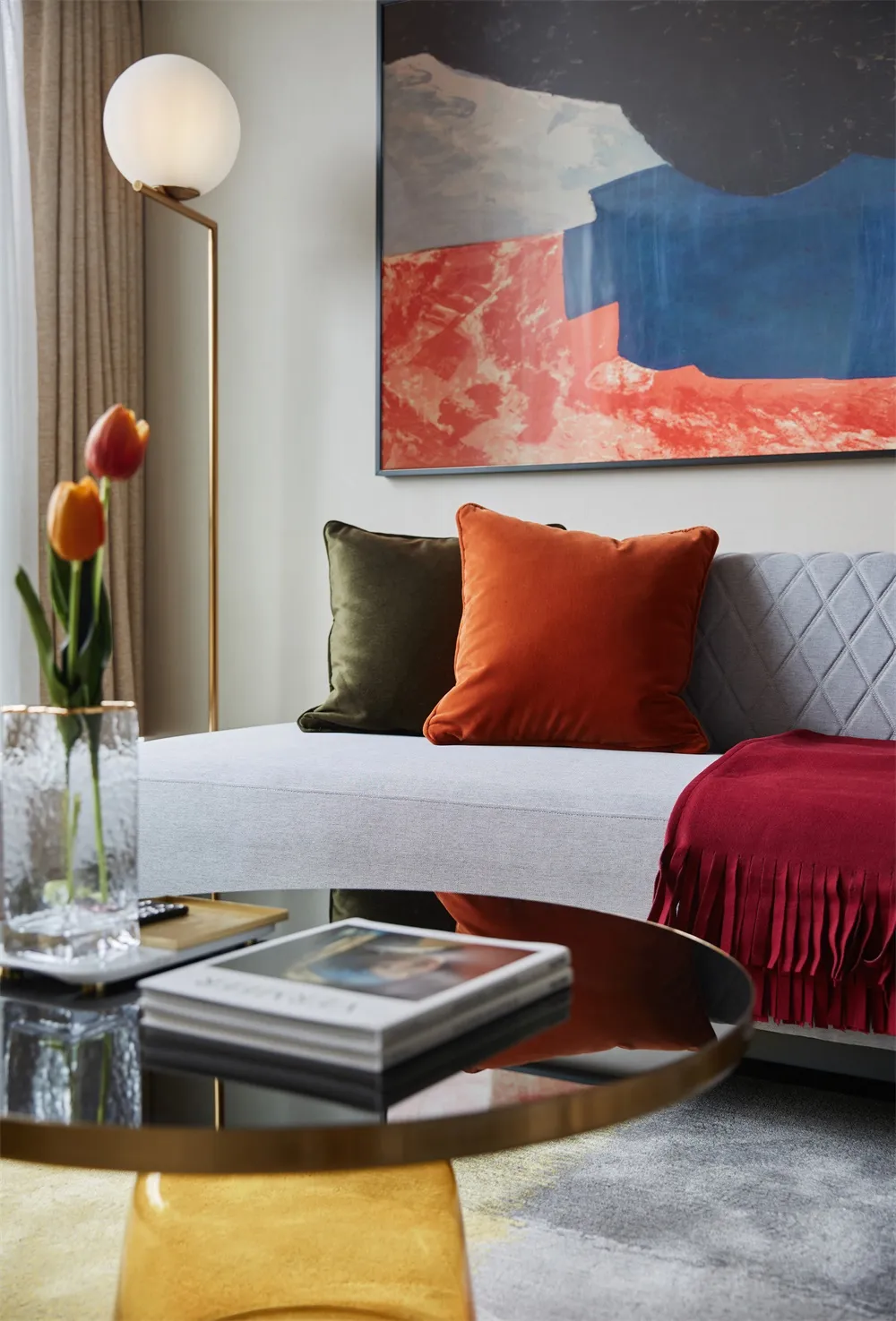 Contemporary living room with a plush gray couch adorned with vibrant orange and green throw pillows and a burgundy throw bla