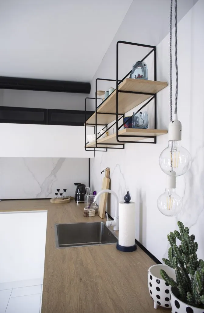 A minimalist kitchen featuring wood countertops, metal shelves, and marble finishes.