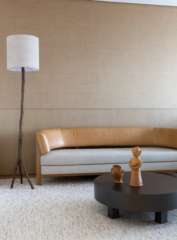 A modern living room with a beige sofa, black coffee table, and decorative statues.