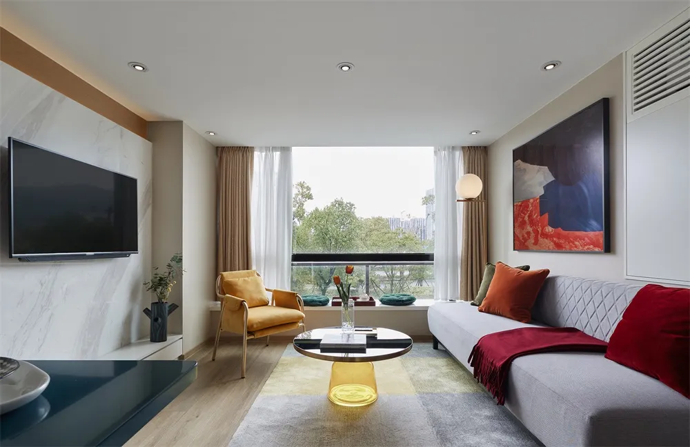 A modern residential living room with floor-to-ceiling windows featuring a sleek sofa, accent chair, and stylish decor.