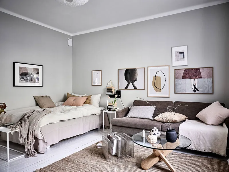 A minimalist living room with light-colored furniture, cushions, and throw blankets.