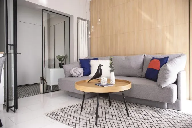 Modern living room featuring a large couch adorned with patterned cushions, surrounded by a wooden coffee table and patterned