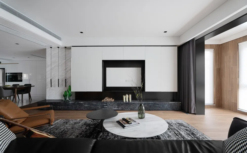 A modern, minimalist living room featuring a marble coffee table and floor, with a black and white color scheme.