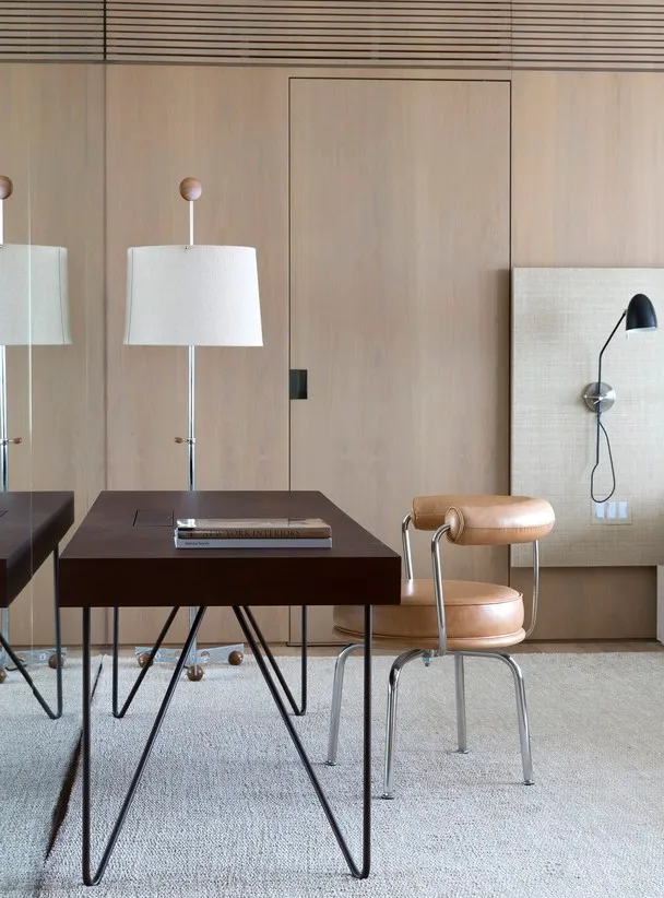 A modern minimalist home office featuring wooden furniture and a white lamp.
