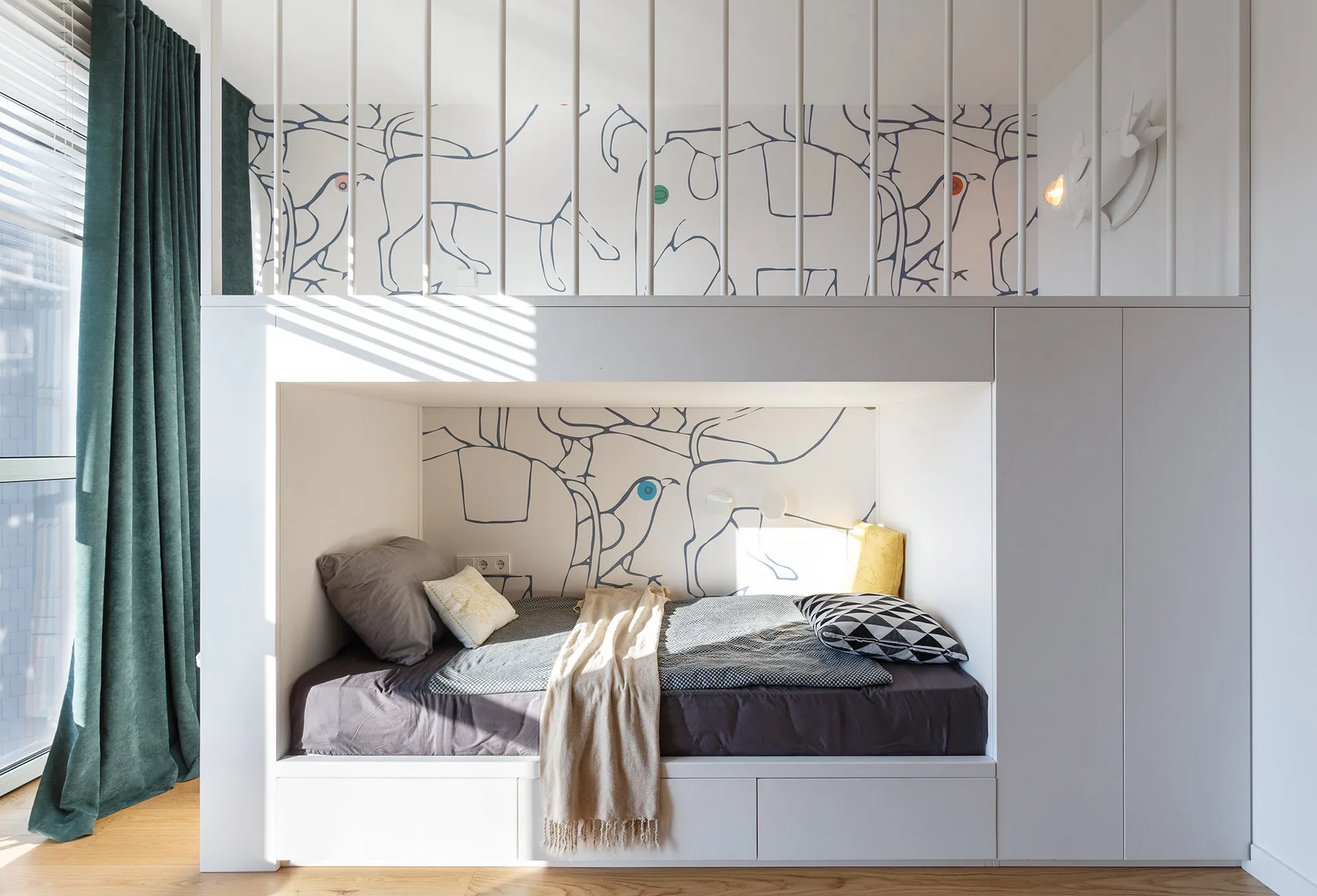 A modern bunkbed space with white walls and wooden floor, featuring a comfortable bed with grey and black bedding and a wall-