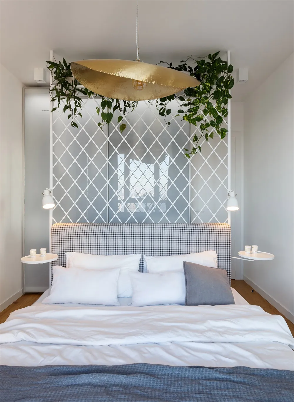 An image of a modern minimalist bedroom with white walls, metal headboard, and white bedding. The room features a geometric h