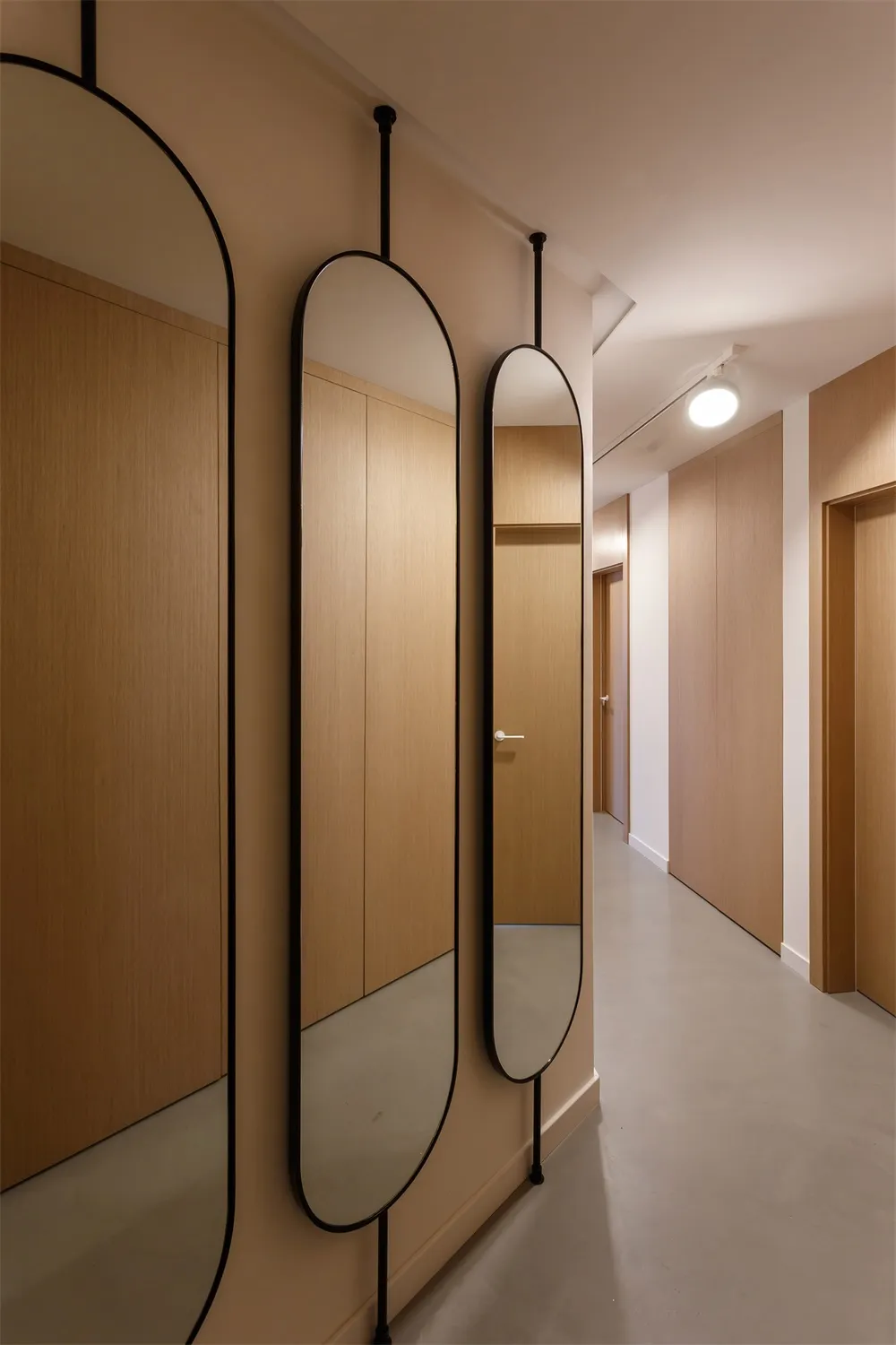 Modern minimalist interior with wooden cabinets and hanging mirrors.
