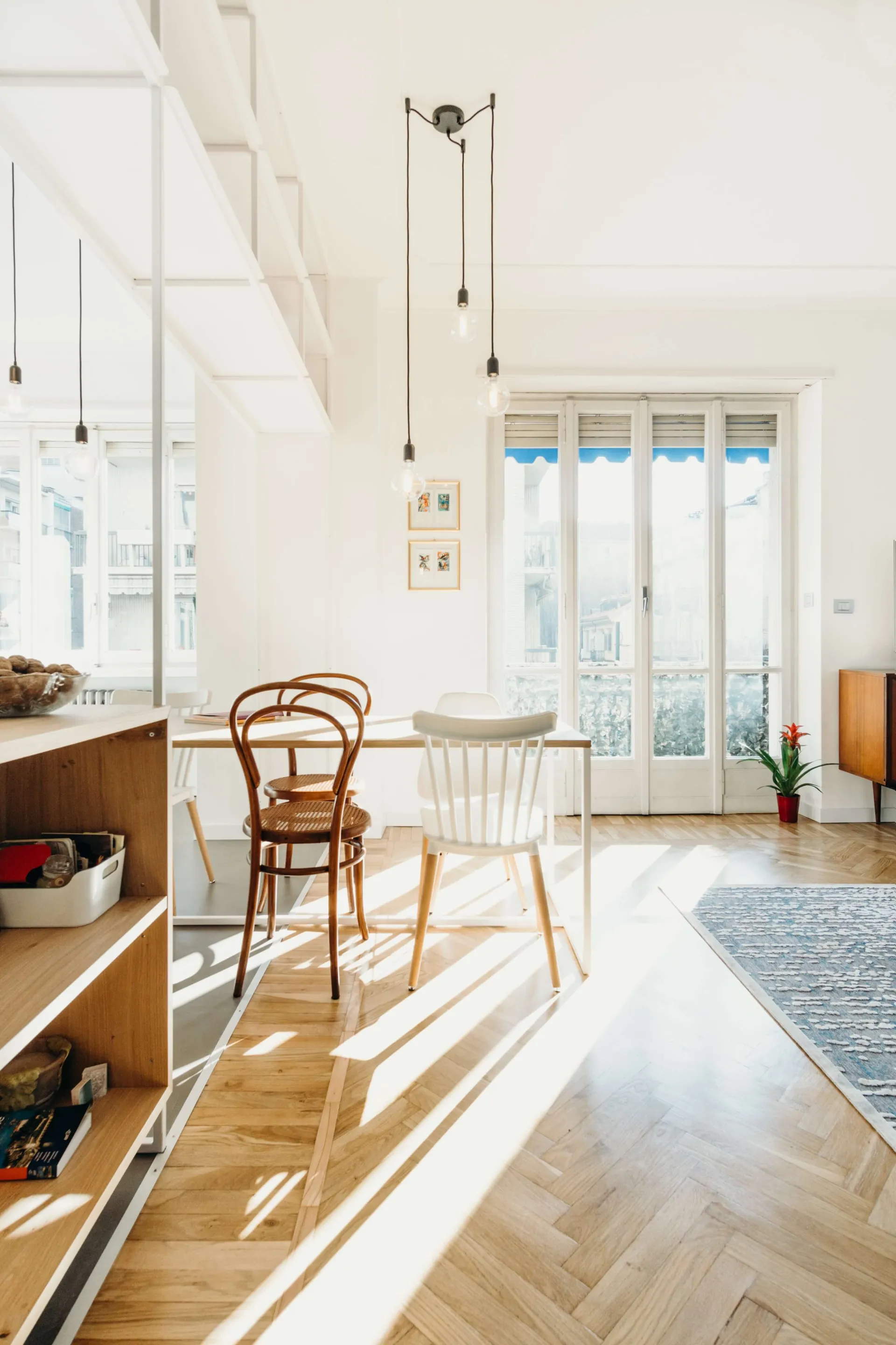 A modern minimalist dining room with wooden flooring, chairs, and a table.