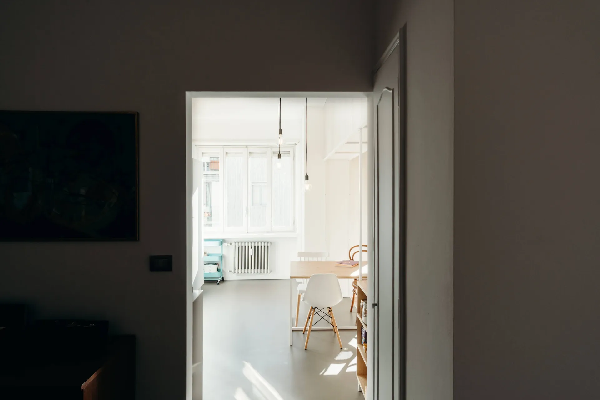 A minimalist interior with white walls, wooden furniture, and a wooden table.