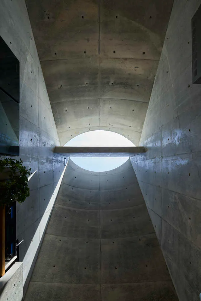 A concrete conduit with a circular opening at the end, showcasing a minimalist architectural design.