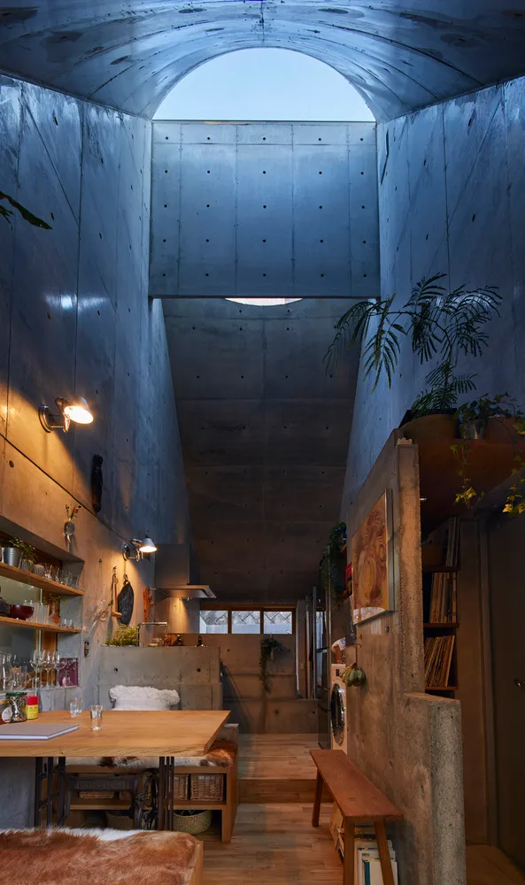 現代工業風住宅室內,裸露混凝土牆面搭配挑高開放天花板,呈現舒適的客廳區域