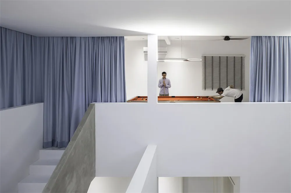 Minimalist living room with concrete walls and floor, featuring a white ceiling and blue curtains.
