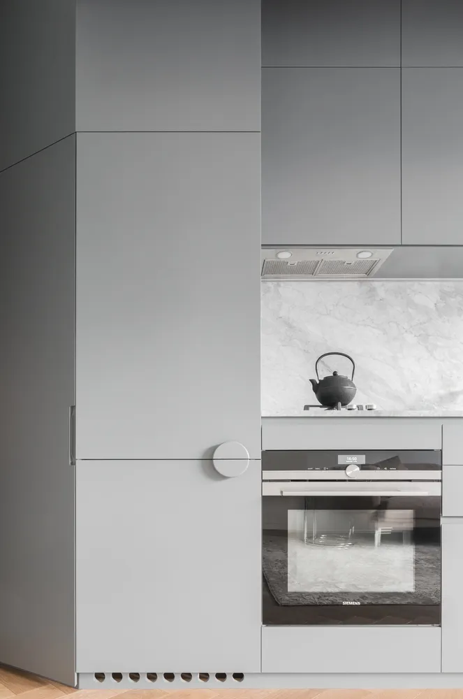 Modern kitchen featuring minimalist design with gray cabinets and appliances.