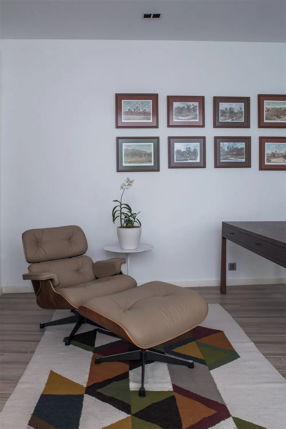 A modern interior lounge featuring a wooden armchair and ottoman with a potted plant.