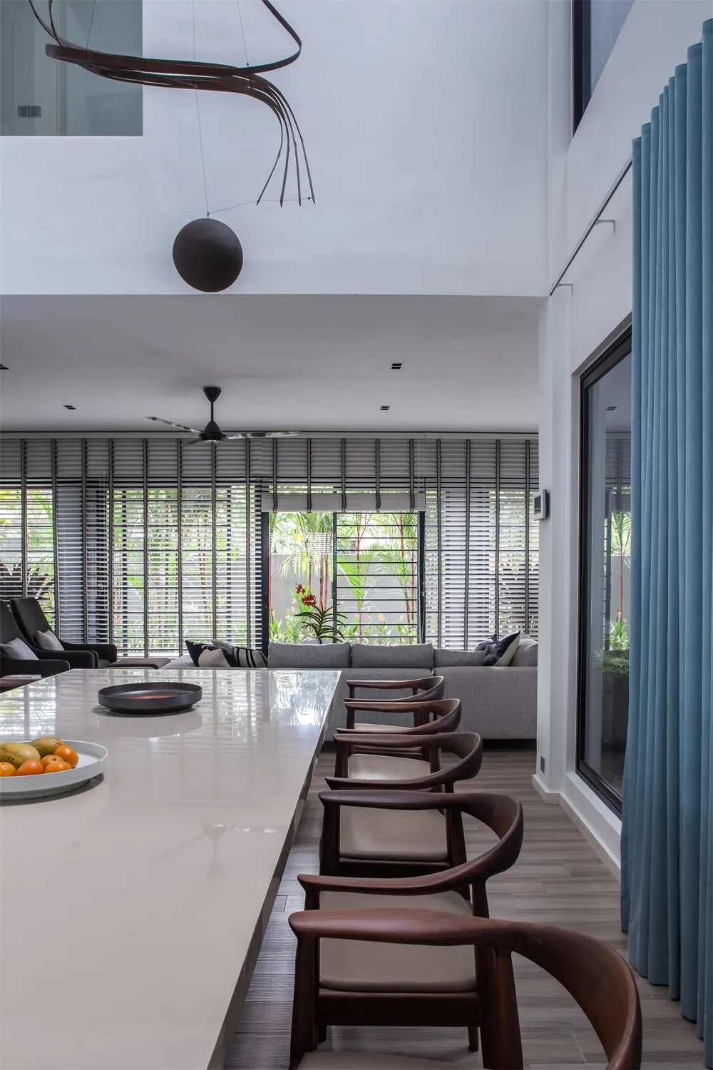 Modern interior design featuring glass, wood, and metal materials in the living and dining area.