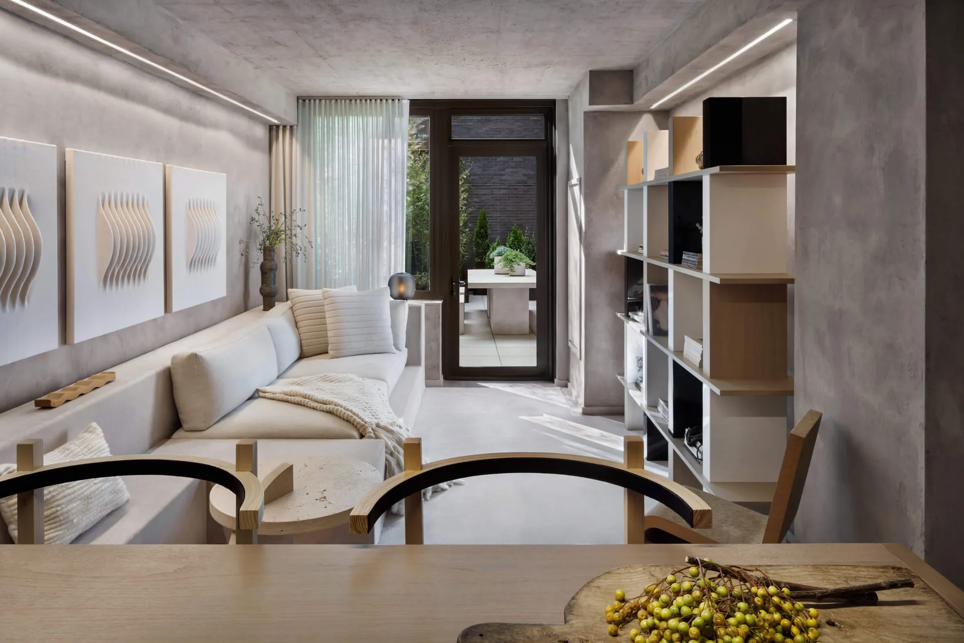 Modern minimalist living room with concrete walls, white sofa, and wooden furniture.