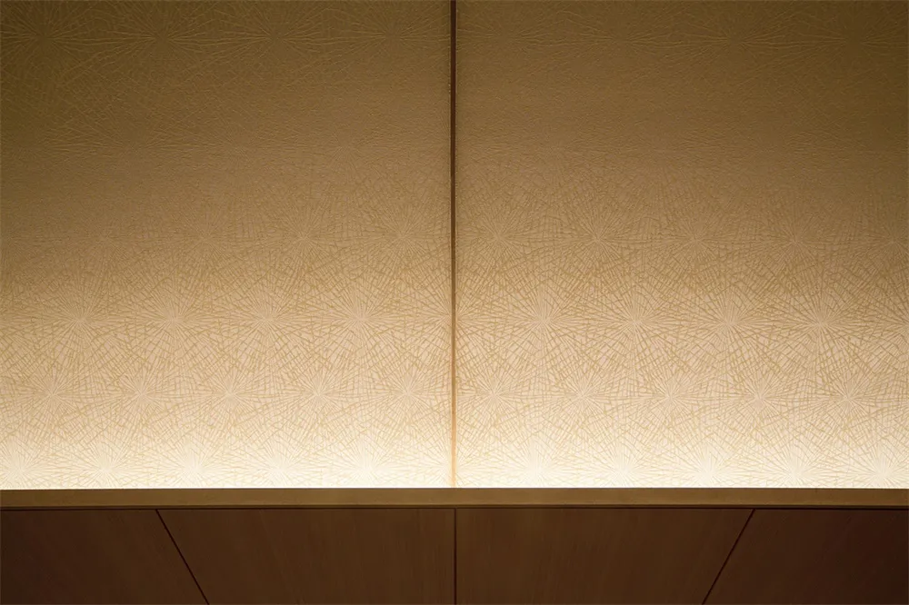 A textured paper wallpaper with illuminated lighting on a wooden wall.
