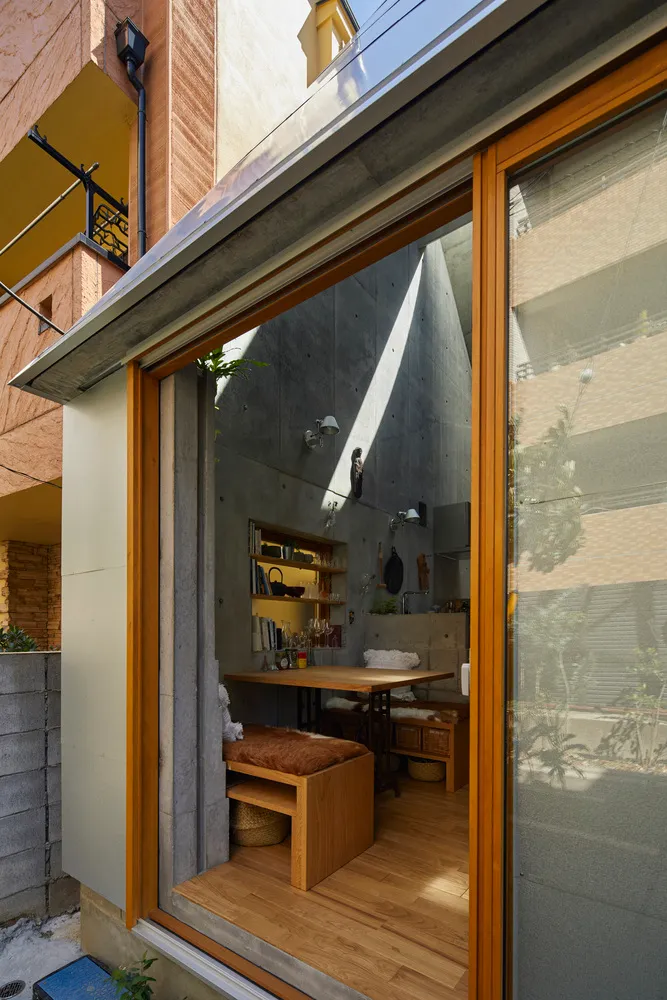 A modern, minimalist kitchen with concrete walls and a small table.
