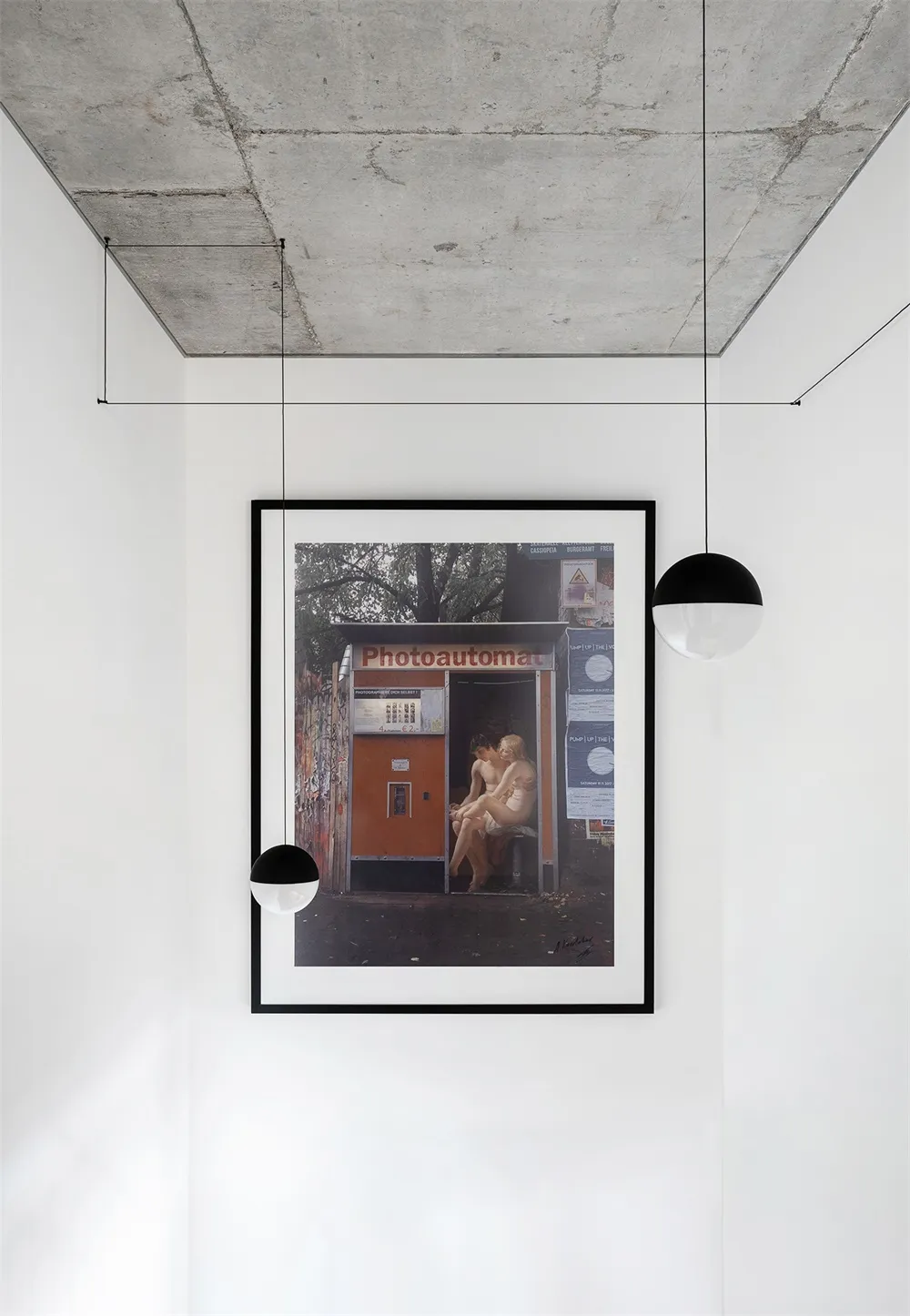 A minimalist photograph framed and displayed in a modern, white room with concrete ceiling.