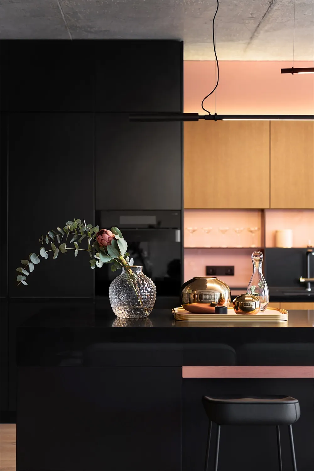 Modern kitchen with black cabinetry, gold tray, and floral decorations.