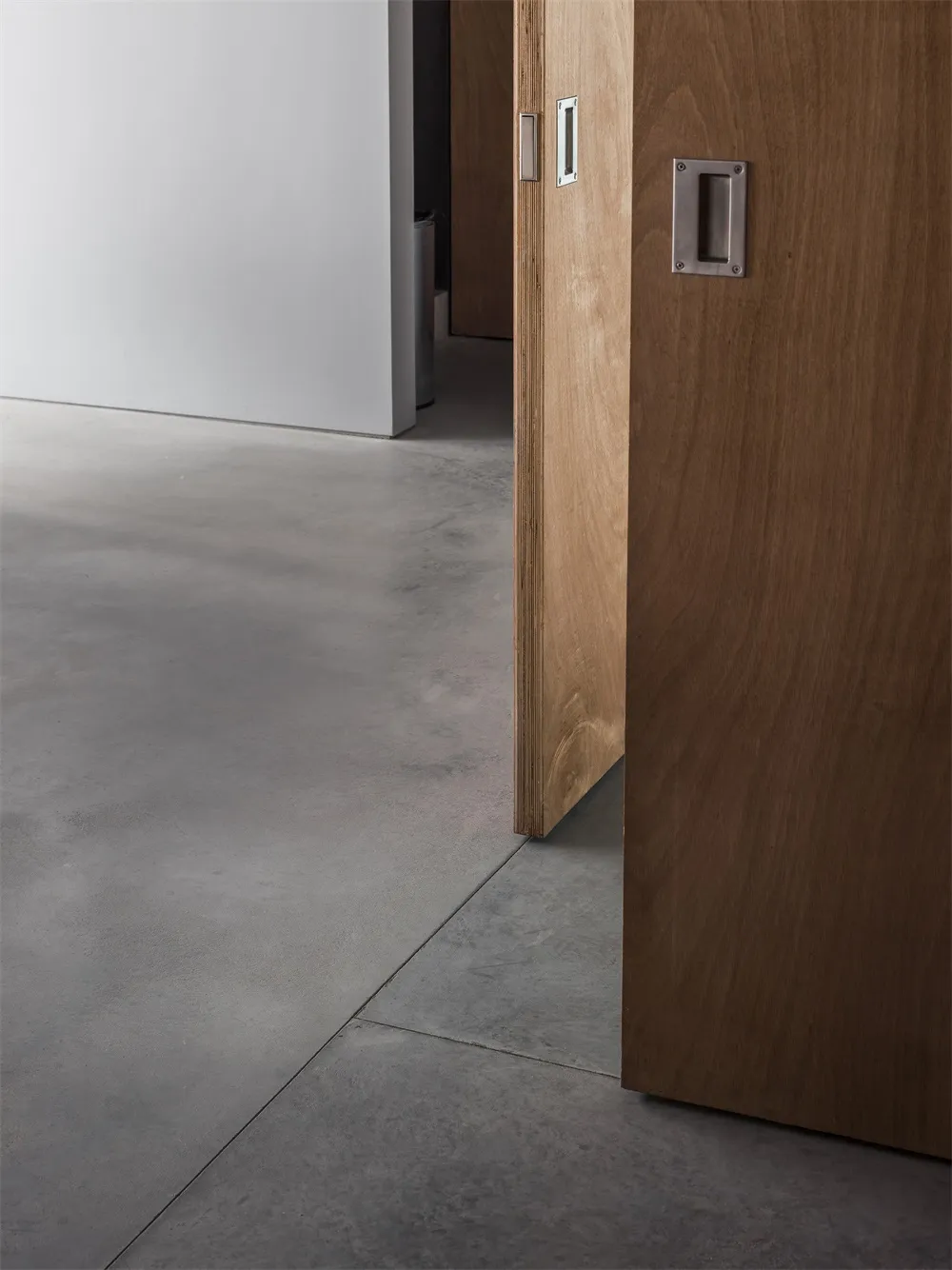 A wooden door with a concrete floor, showing a minimalist and modern aesthetic.