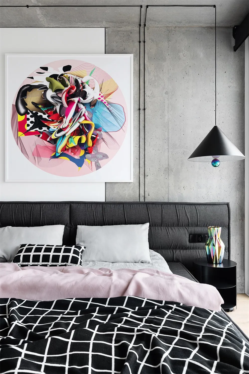 A modern minimalist bedroom with a grey bed, pink accents, and abstract art hanging above the headboard.
