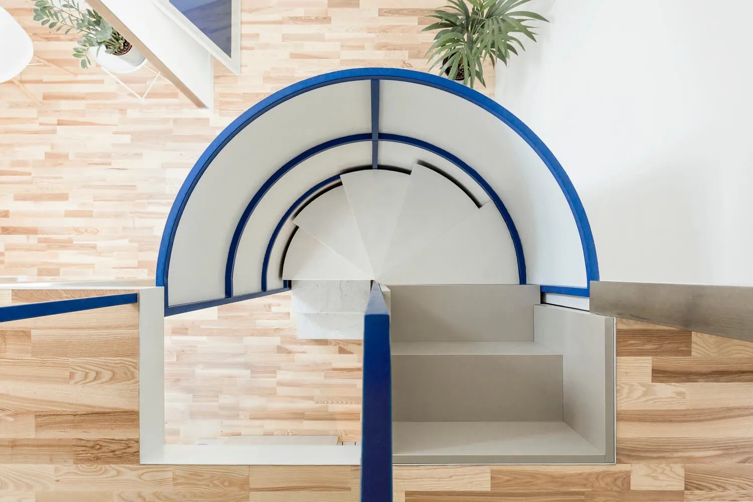 A modern, open-space staircase with a wood floor and white structures.