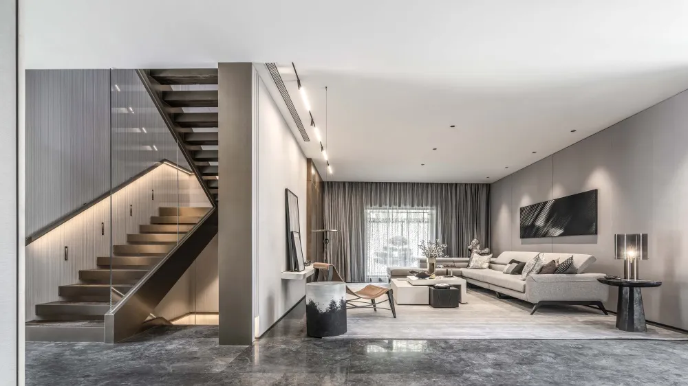 Modern white living room with glass stairwell, concrete flooring, and metal staircase.