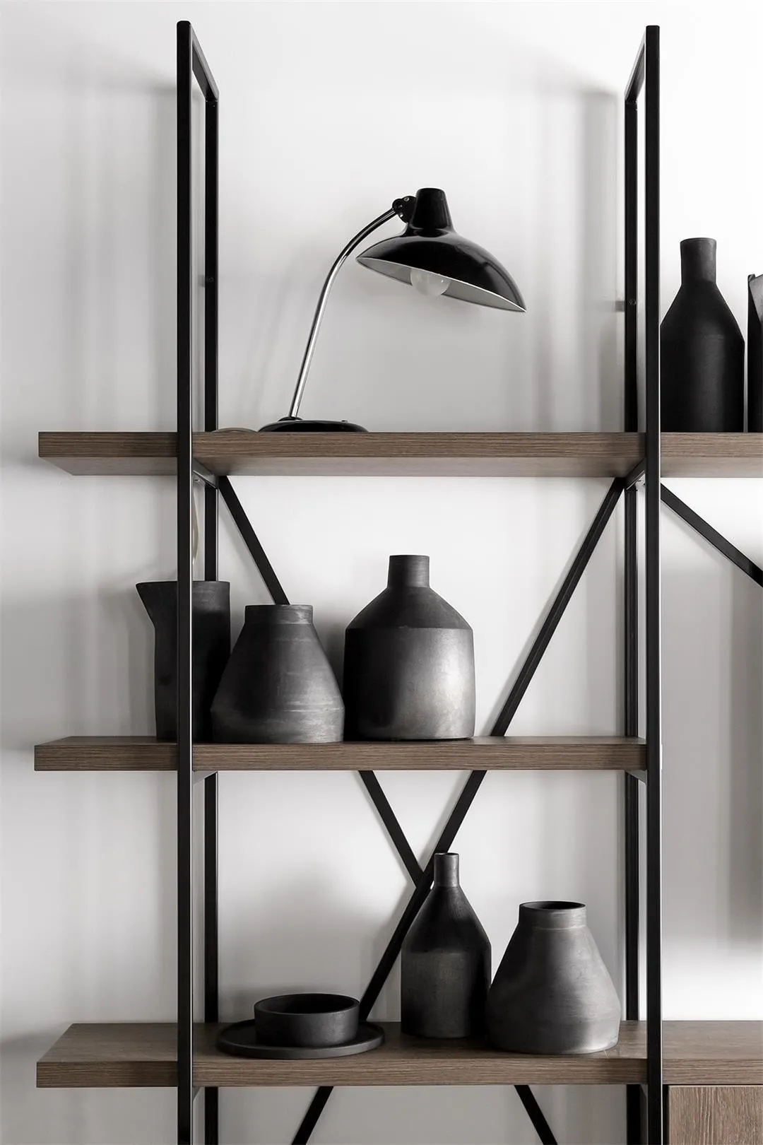 Modern shelves displaying black ceramic vases and a black lamp against a white background.