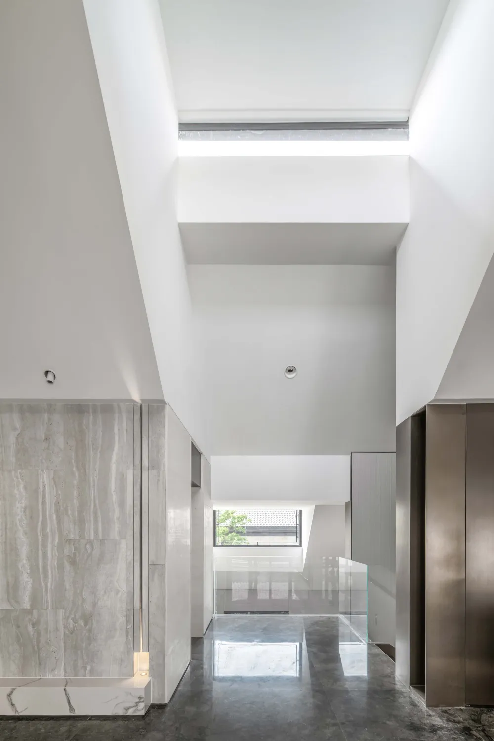 Modern residential entrance featuring concrete, glass, and marble materials.