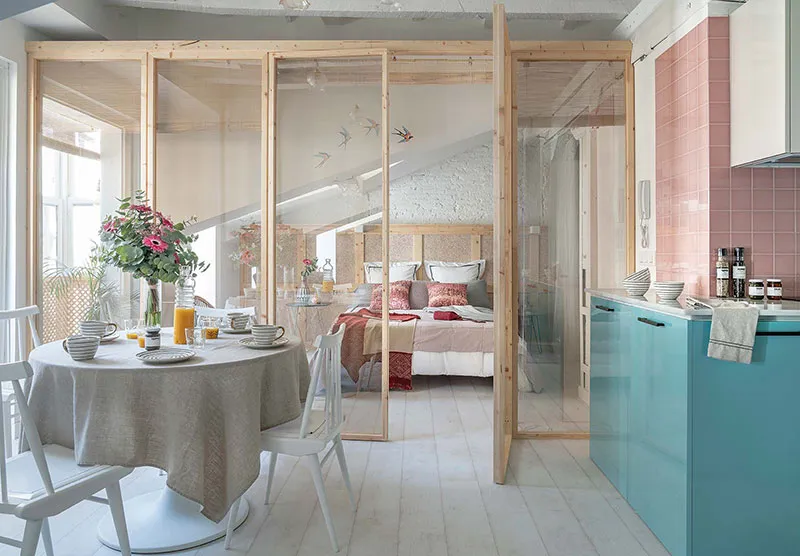 A modern dining room in a minimalist apartment, featuring a round table with a beige cloth, white chairs, and a view into the