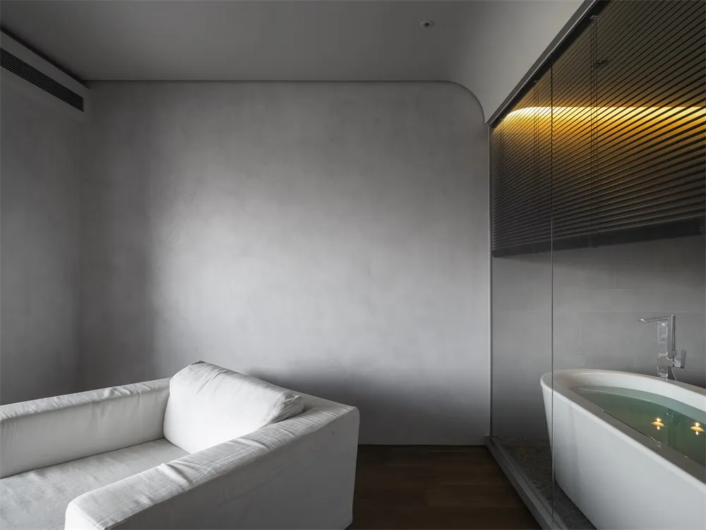 Modern minimalist bathroom with concrete walls, glass shower enclosure, and wooden floor.