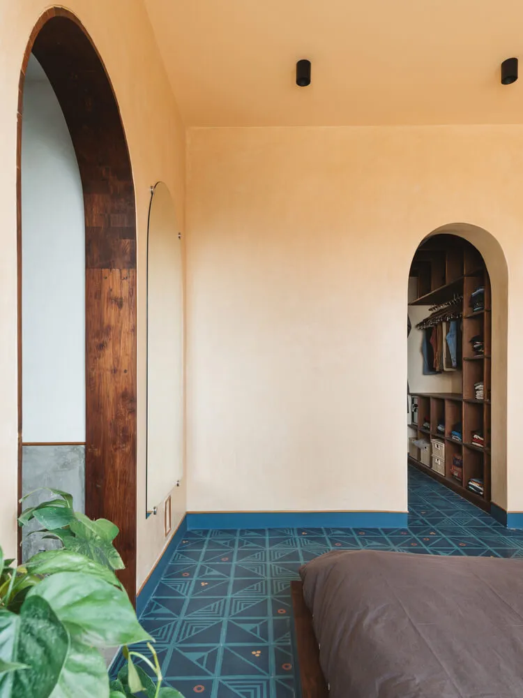 An image of a minimalist bedroom with concrete walls and patterned flooring.