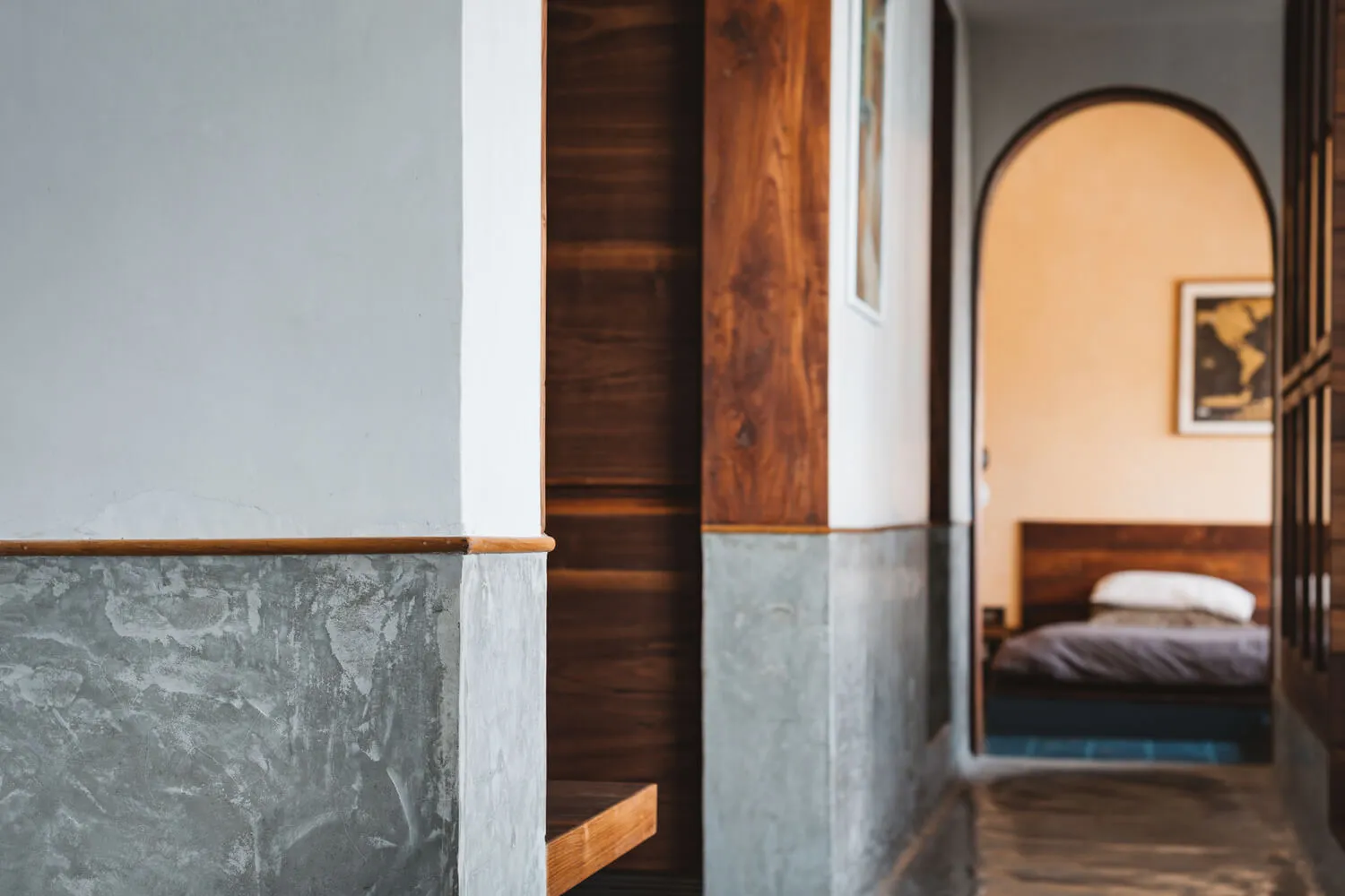 A minimalist bedroom with concrete, wood, and metal elements.