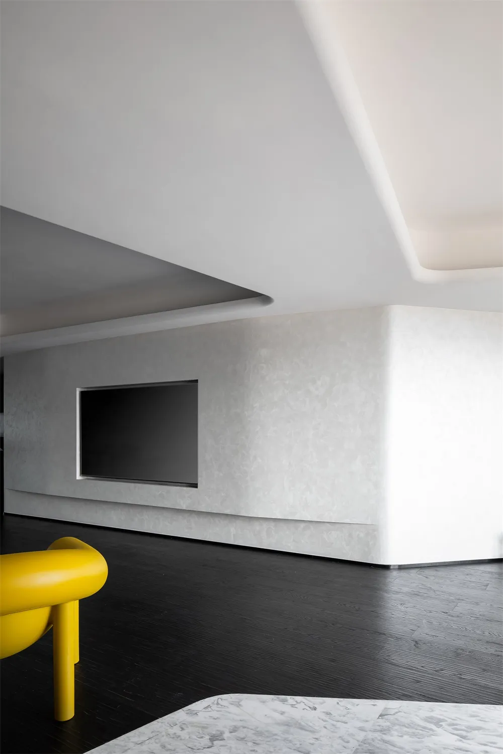 A minimalist living room features a sleek, modern design with white and black tones, accentuated by a bright yellow chair and