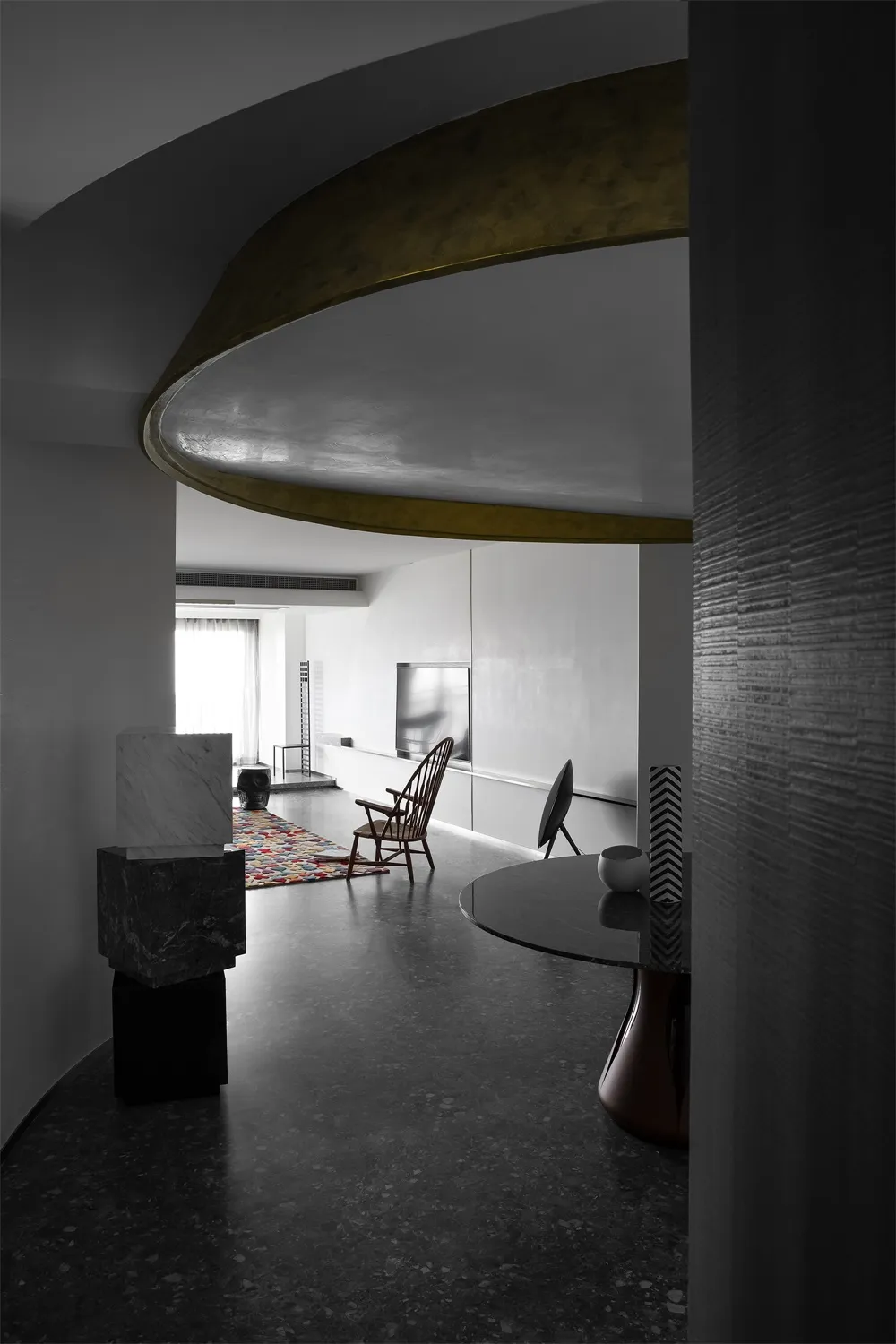 A modern interior featuring concrete elements, minimalist furniture, and a circular architectural design.
