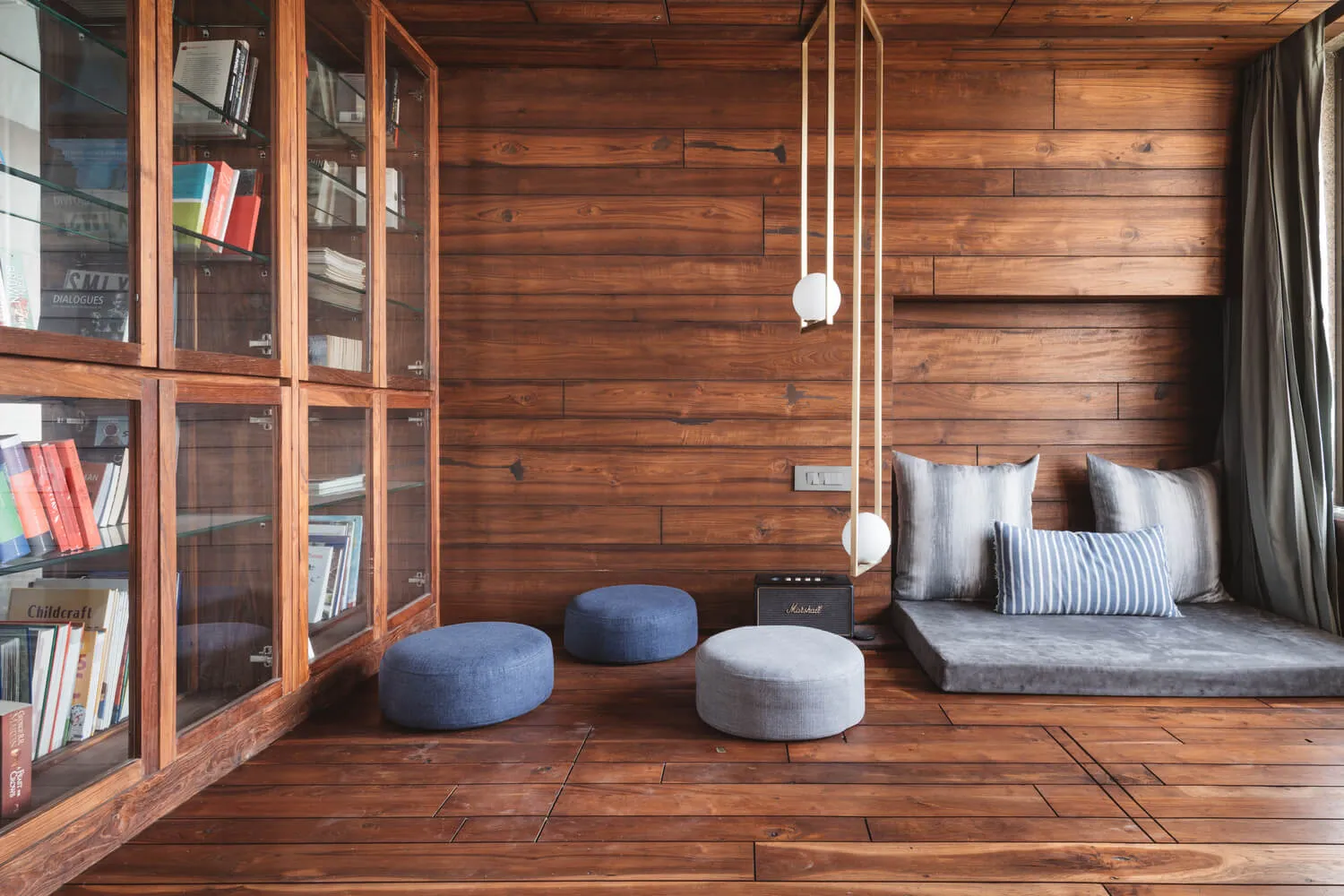 A minimalist living room with wood-paneled walls, a bookshelf, and seating area.