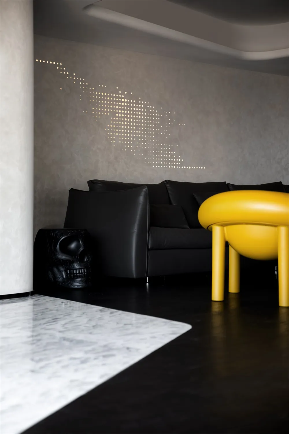 Modern living room with black leather sofa, marble coffee table, and sleek design elements.