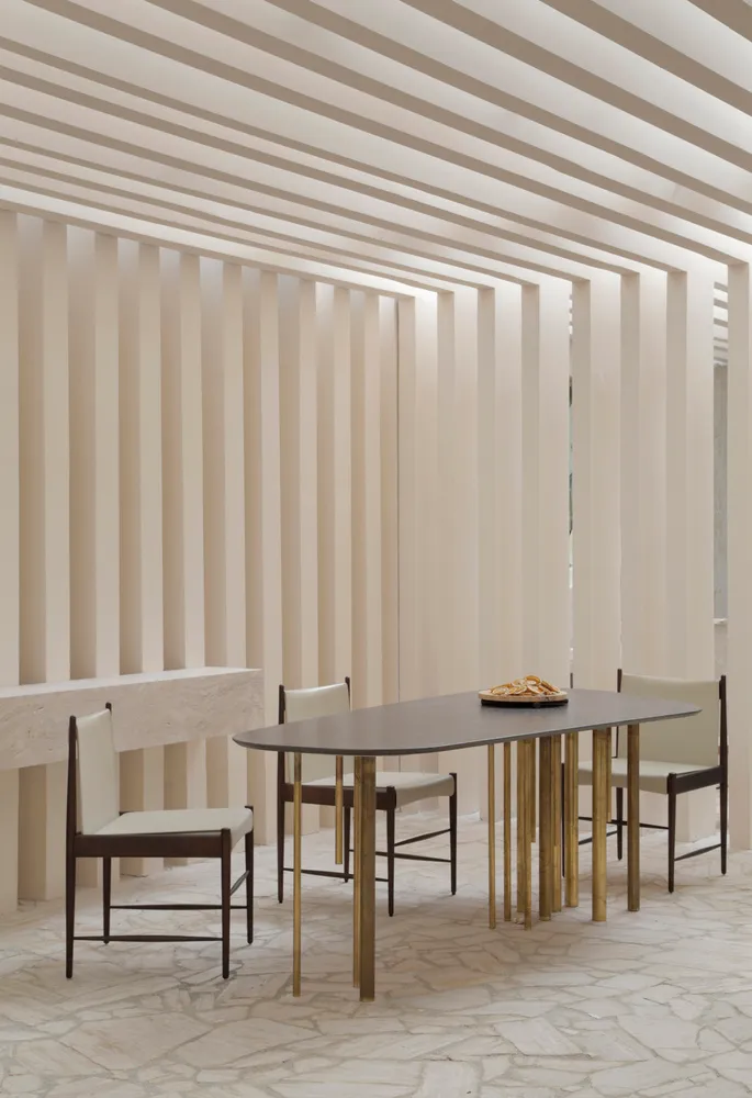 Modern dining room featuring wooden and brass furniture, with a minimalist design aesthetic.