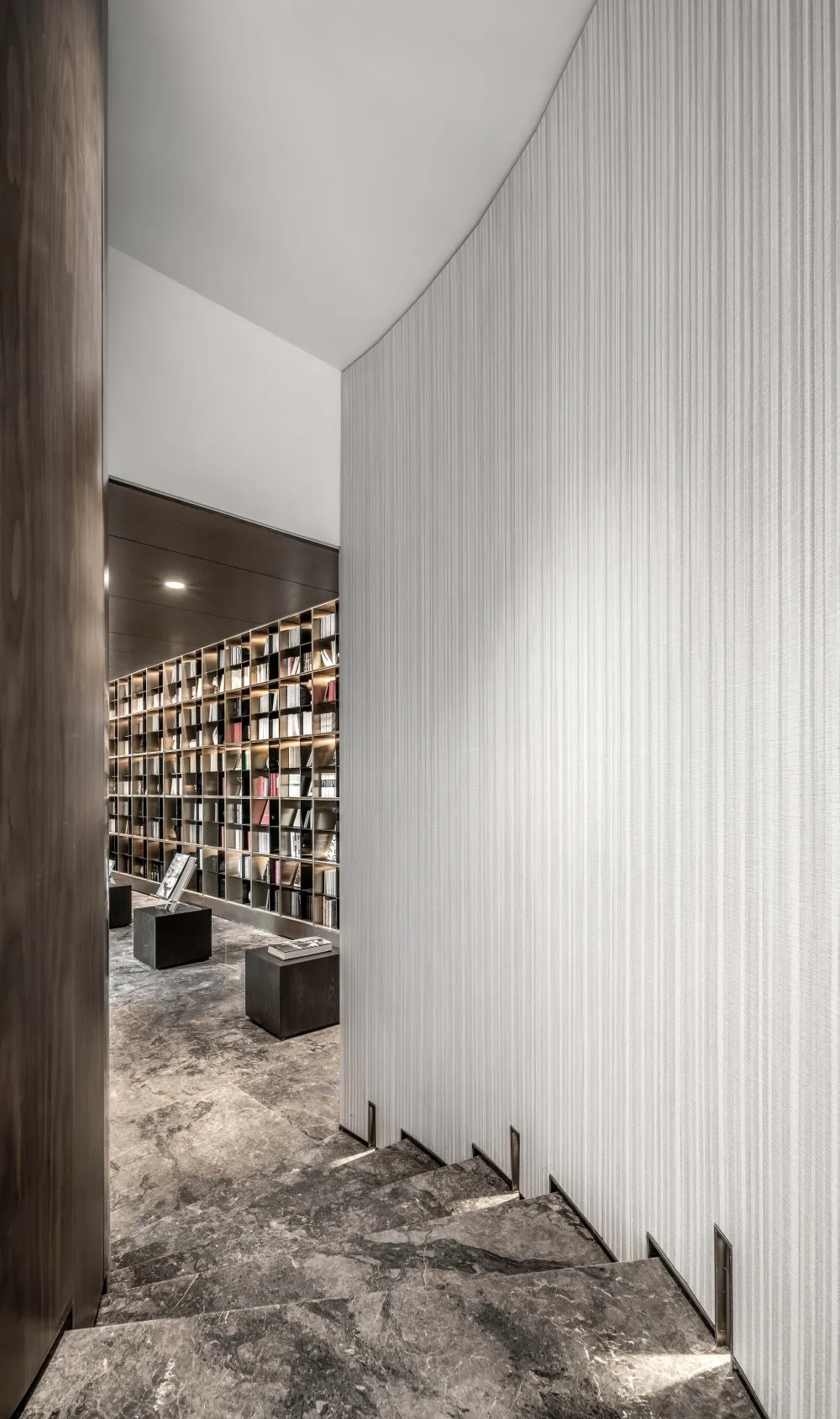 A modern library staircase made of marble with a view of a bookshelf.