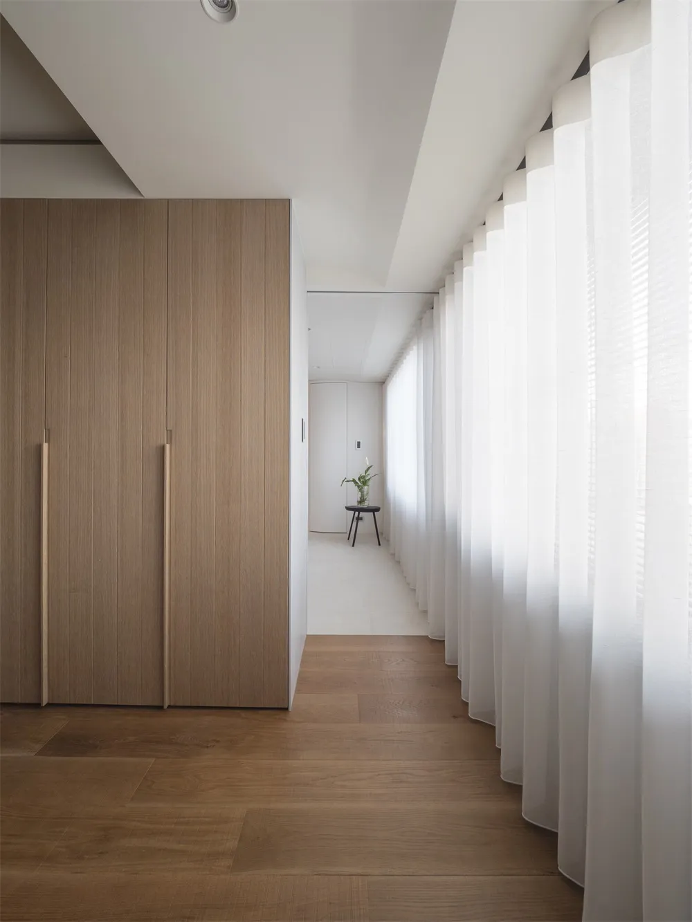 Modern minimalist interior with wooden furniture and white curtains.