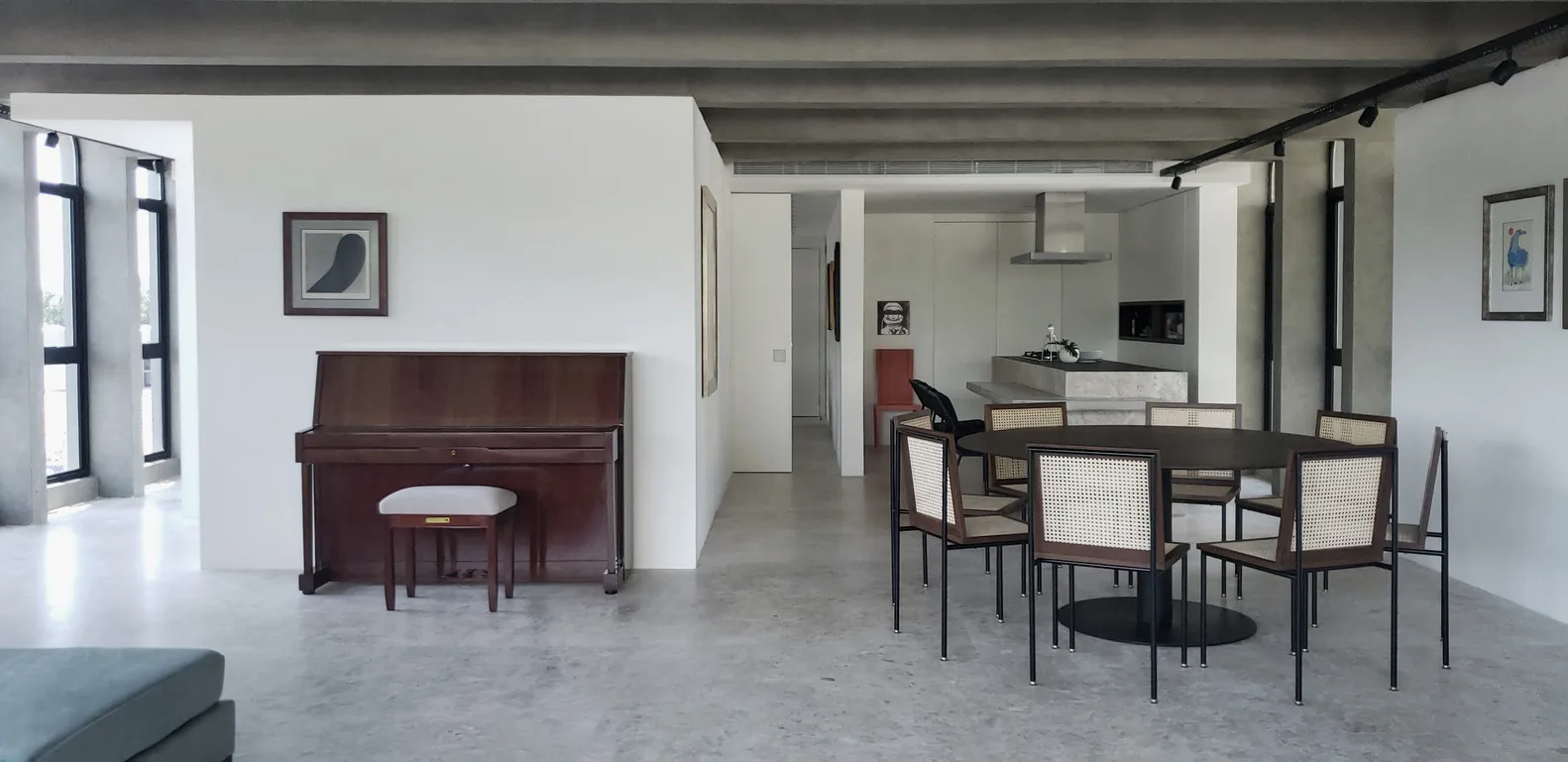 Modern, minimalist living room with a large window, concrete floor, and black furniture.
