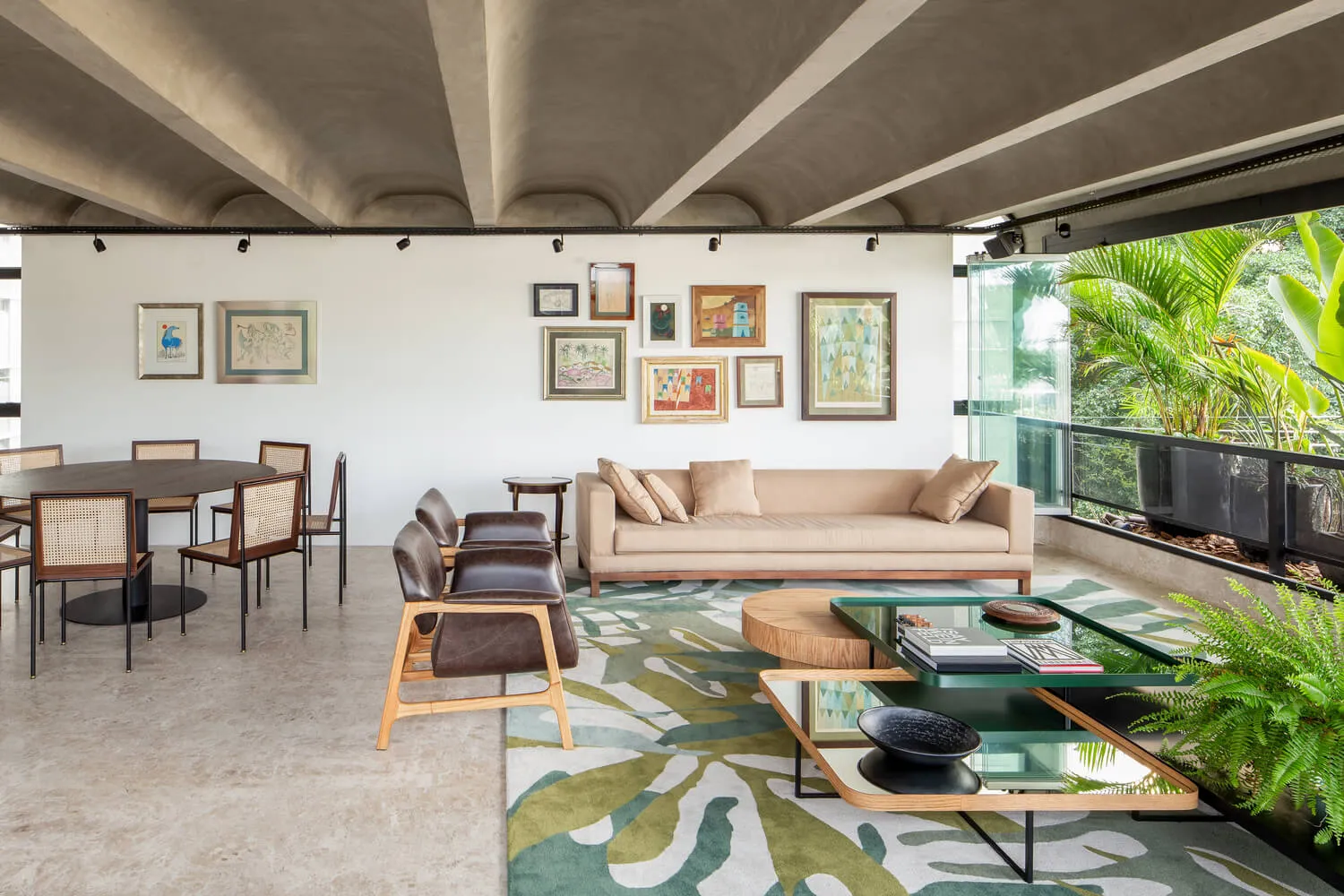 A modern living room featuring a concrete floor and walls, with a beige sofa and abstract art on the walls.