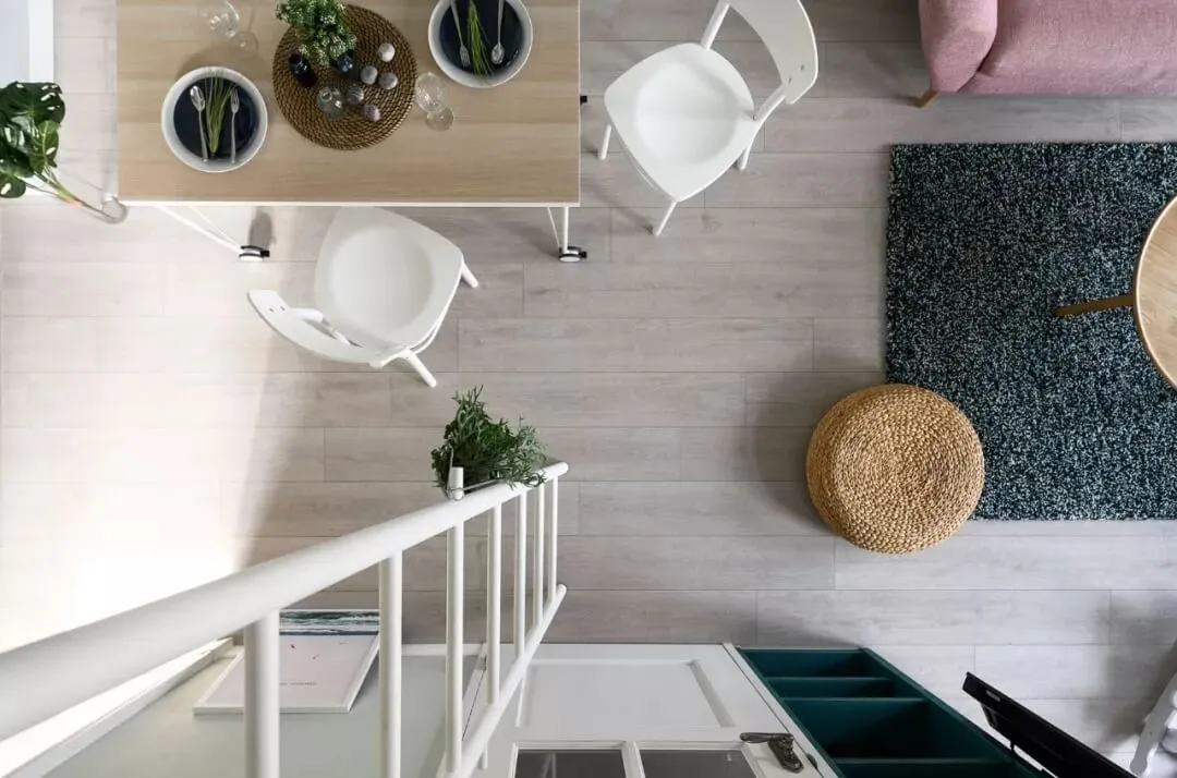 View of a minimalist living room with wooden furniture and decor, including a rug and a chair.