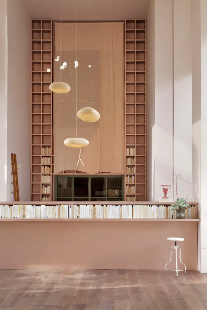 A modern library with glass shelves, wooden reception desk, and metal stools.