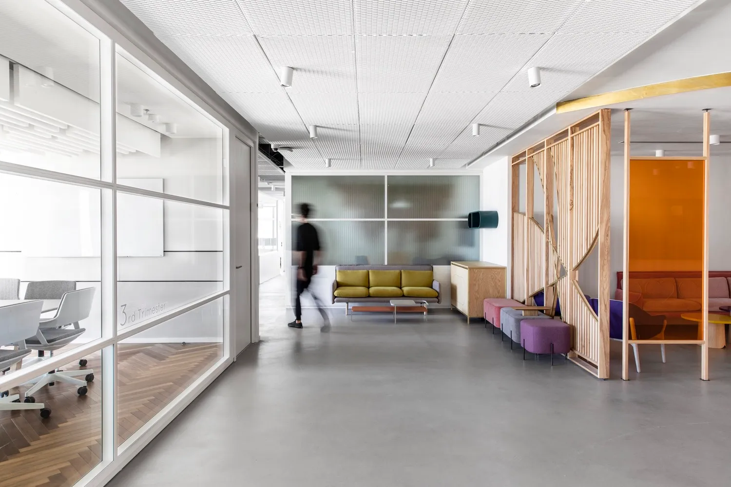 A modern office lounge with glass panels, a concrete floor, and minimalistic design elements.
